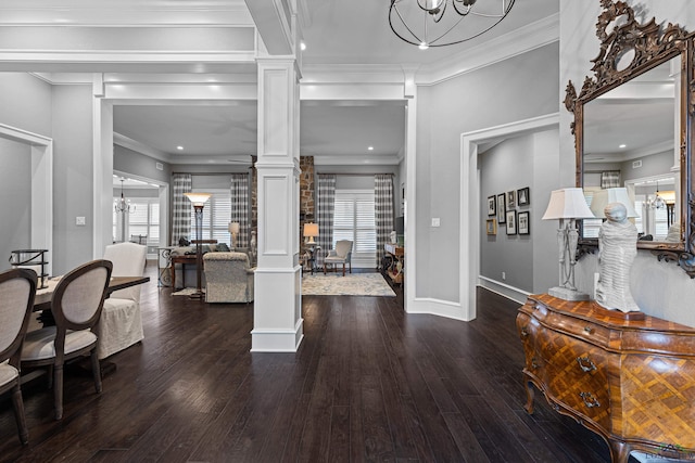 entrance foyer with crown molding, a notable chandelier, decorative columns, and wood finished floors