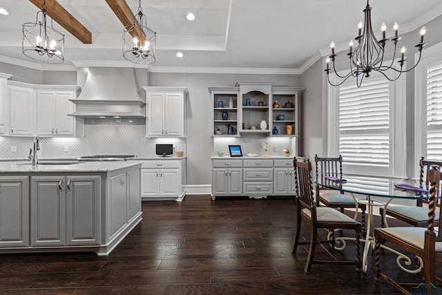 kitchen featuring dark wood-style flooring, gray cabinets, decorative backsplash, ornamental molding, and wall chimney exhaust hood