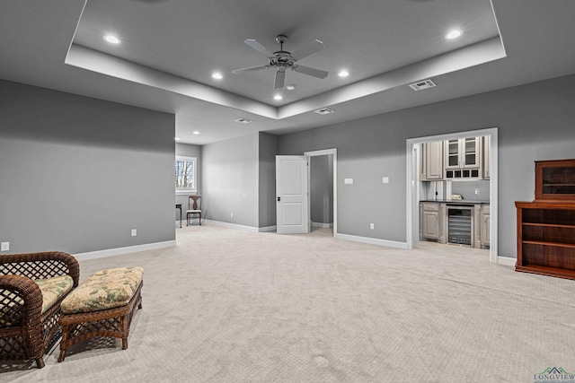 sitting room with beverage cooler, light carpet, a raised ceiling, and visible vents