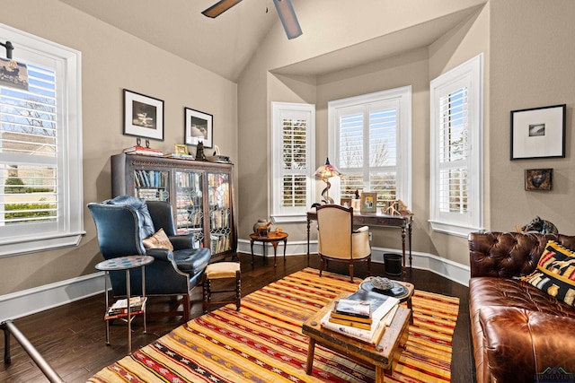 living area featuring a healthy amount of sunlight, baseboards, vaulted ceiling, and wood finished floors