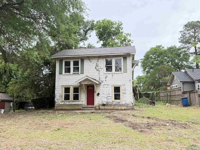 colonial inspired home featuring fence and a front lawn