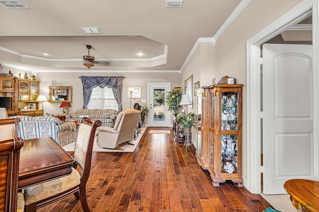 living room featuring a tray ceiling, ceiling fan, crown molding, and dark hardwood / wood-style floors