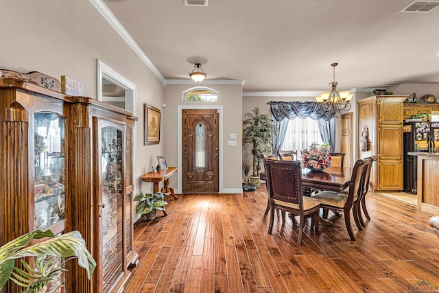 dining room featuring light hardwood / wood-style floors, crown molding, and a chandelier