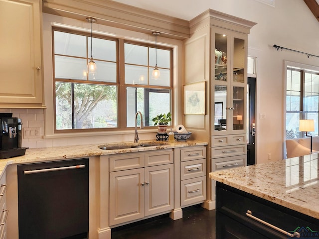 kitchen featuring pendant lighting, dishwasher, sink, decorative backsplash, and light stone countertops