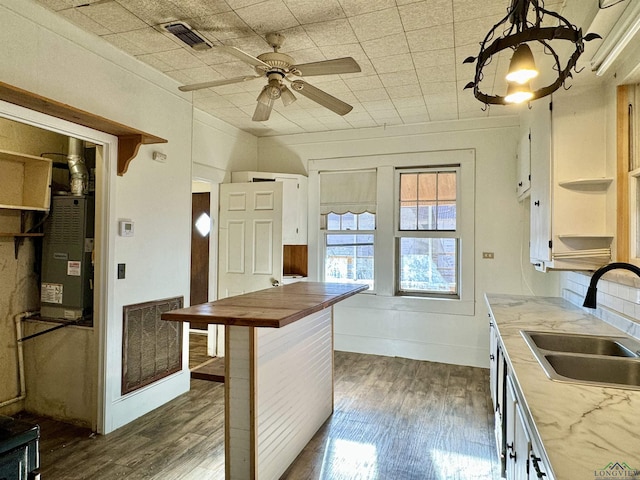 kitchen featuring sink, wood counters, pendant lighting, dark hardwood / wood-style flooring, and a breakfast bar area