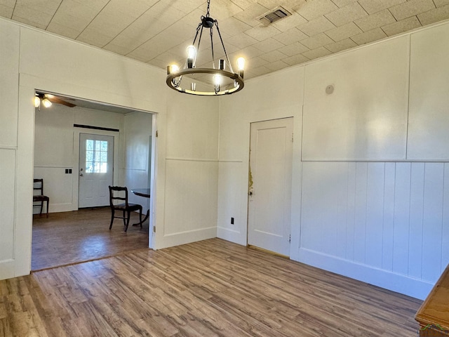 unfurnished dining area featuring wood-type flooring and a notable chandelier