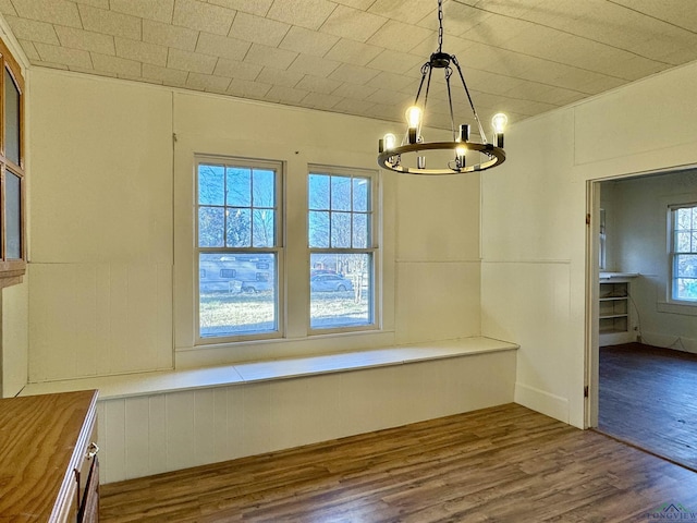 unfurnished dining area featuring wood-type flooring and a notable chandelier