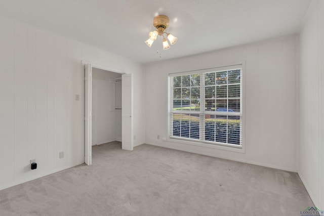 unfurnished room with light carpet, ceiling fan, and wood walls