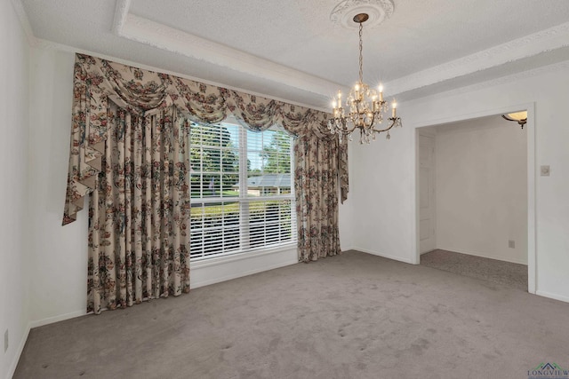 empty room with a raised ceiling, carpet, a chandelier, and a textured ceiling