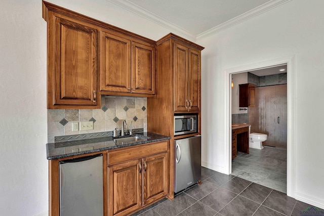 kitchen featuring stainless steel microwave, sink, dark tile patterned floors, refrigerator, and ornamental molding