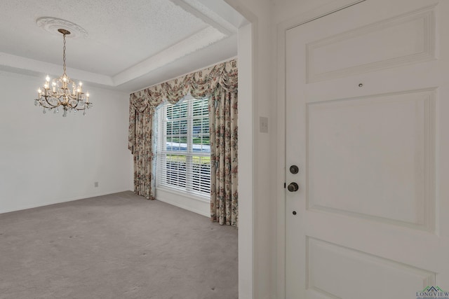 interior space with a textured ceiling, light colored carpet, a raised ceiling, and a notable chandelier