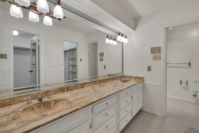 bathroom with tile patterned flooring, vanity, a textured ceiling, and a notable chandelier