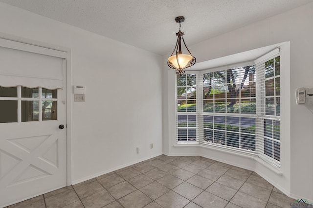 unfurnished dining area featuring light tile patterned floors and a textured ceiling