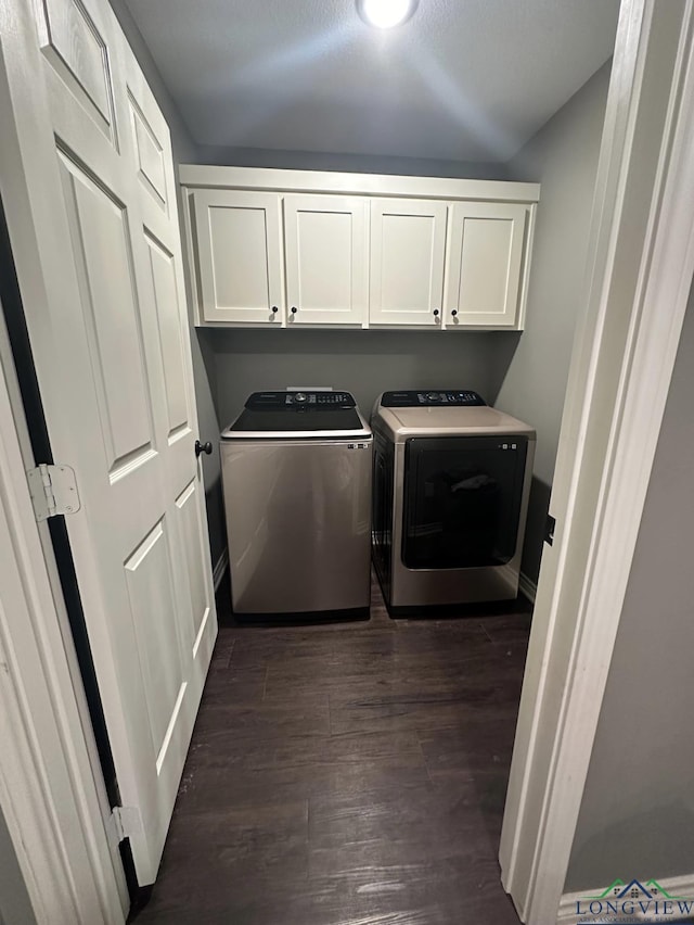 laundry area with dark wood-style flooring, washing machine and clothes dryer, and cabinet space