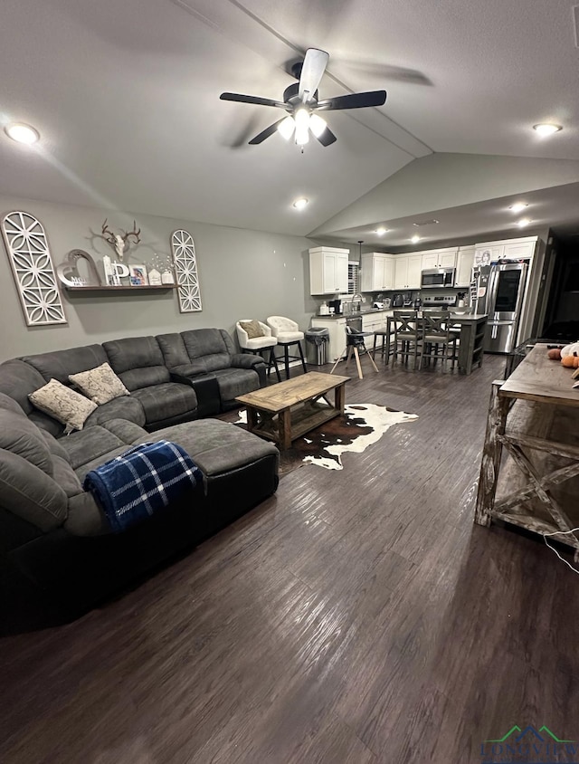 living room featuring ceiling fan, dark wood-type flooring, and lofted ceiling