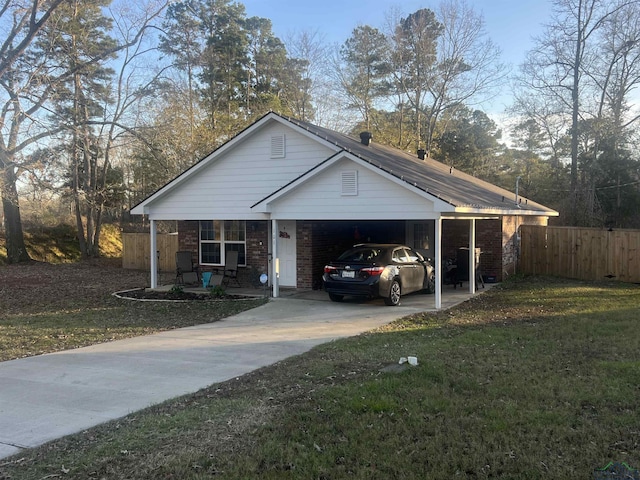 view of front of house with a carport, concrete driveway, fence, and a front lawn