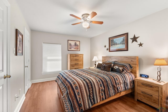 bedroom featuring a ceiling fan, baseboards, and wood finished floors