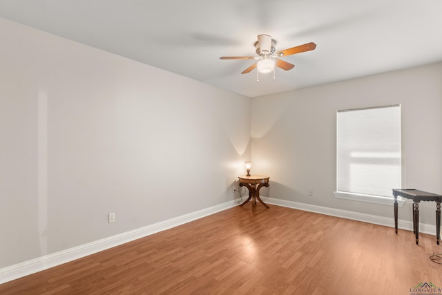 empty room with a ceiling fan, light wood-style floors, and baseboards