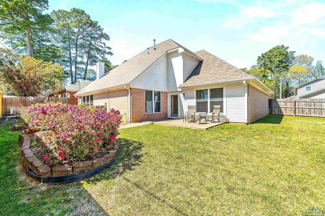 rear view of house featuring brick siding, a fenced backyard, a patio area, and a lawn