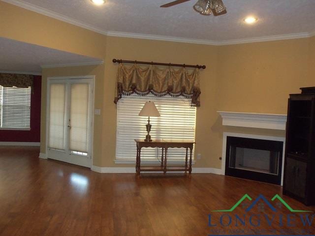 unfurnished living room featuring ceiling fan, wood-type flooring, a textured ceiling, and ornamental molding