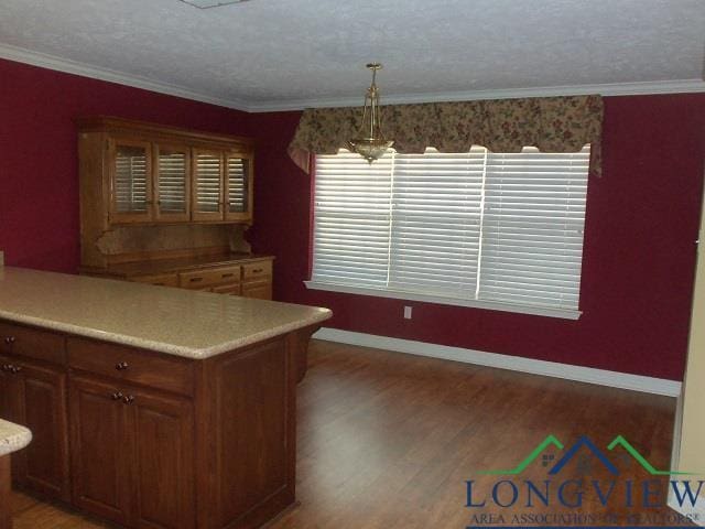 kitchen with pendant lighting, an inviting chandelier, crown molding, dark hardwood / wood-style floors, and kitchen peninsula