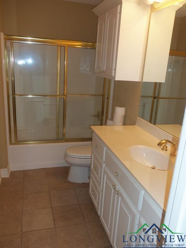 full bathroom with tile patterned floors, toilet, combined bath / shower with glass door, and vanity