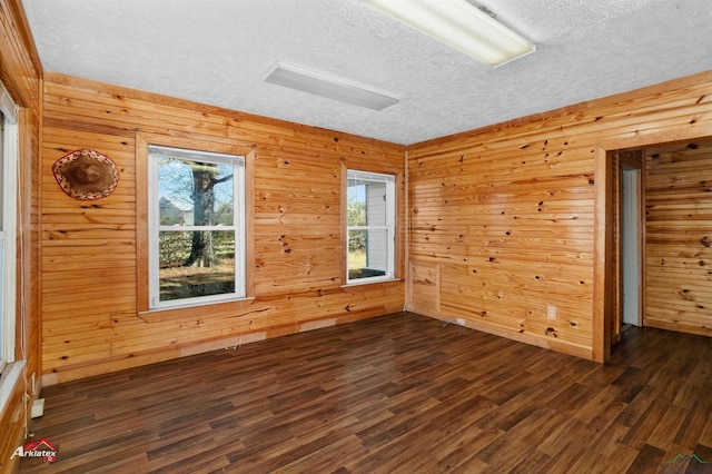 spare room with dark hardwood / wood-style flooring and wooden walls