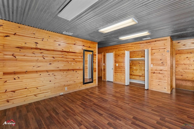 spare room with wooden walls and dark wood-type flooring