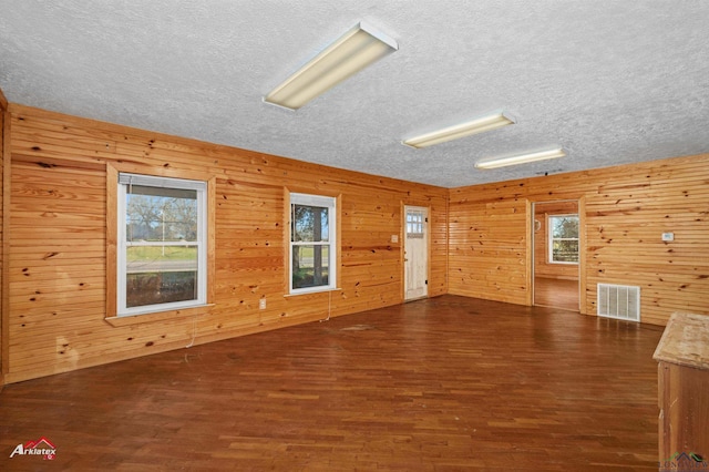 spare room featuring wood walls and dark hardwood / wood-style floors