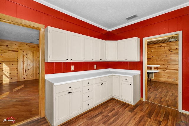 kitchen with dark wood-type flooring, white cabinetry, and crown molding