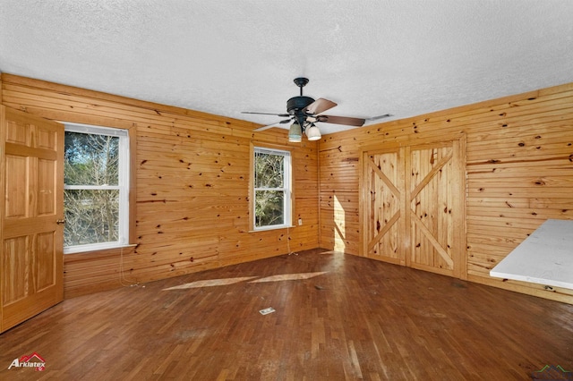 spare room featuring hardwood / wood-style floors, wood walls, and a textured ceiling