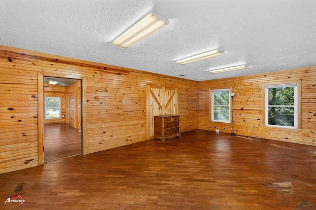 unfurnished room with wooden walls, dark hardwood / wood-style flooring, and plenty of natural light