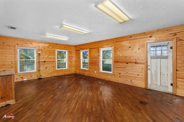 unfurnished room with dark hardwood / wood-style flooring and wood walls