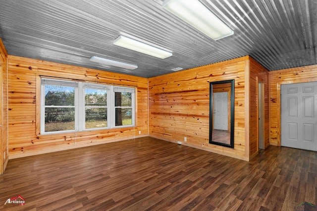 spare room featuring dark wood-type flooring and wooden walls