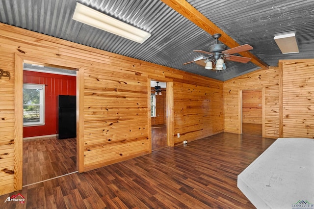 spare room with vaulted ceiling with beams, dark hardwood / wood-style flooring, ceiling fan, and wooden walls