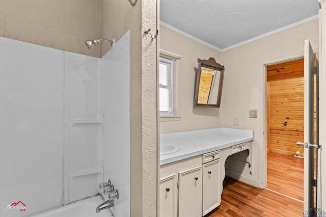 bathroom with hardwood / wood-style floors, vanity, shower / washtub combination, ornamental molding, and a textured ceiling