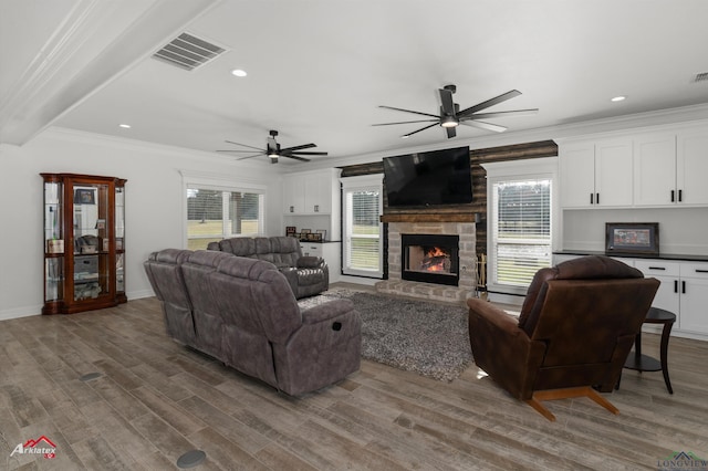 living area featuring visible vents, plenty of natural light, wood finished floors, and crown molding