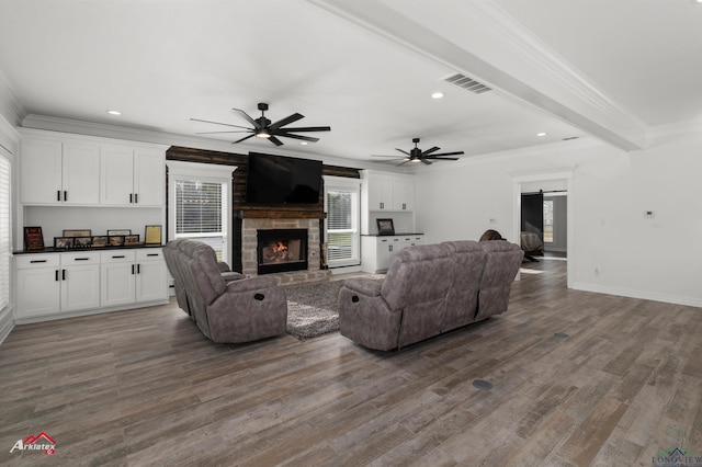 living area featuring visible vents, a barn door, wood finished floors, and crown molding