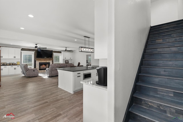 staircase featuring a lit fireplace, ornamental molding, recessed lighting, wood finished floors, and a ceiling fan