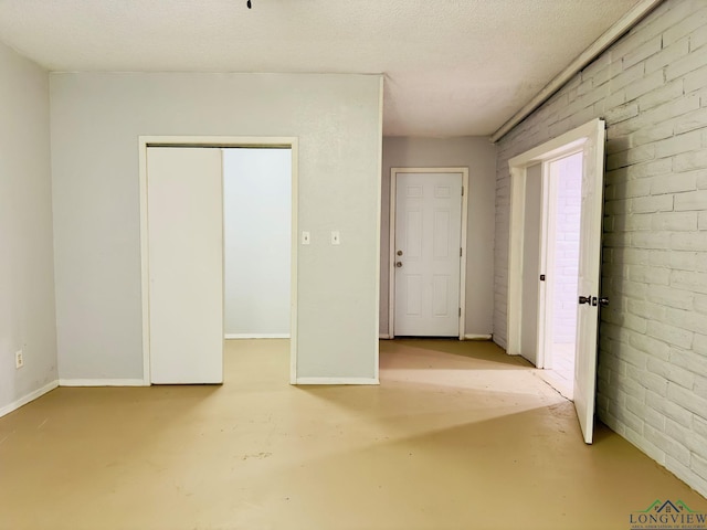 empty room featuring a textured ceiling and brick wall