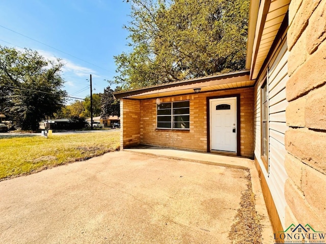 entrance to property featuring a lawn and a patio area