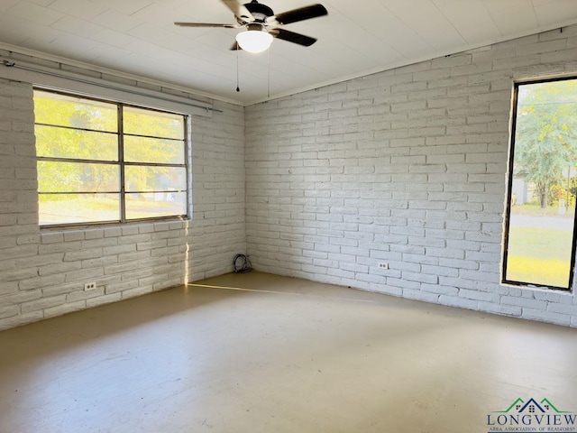 spare room featuring plenty of natural light, brick wall, and concrete floors