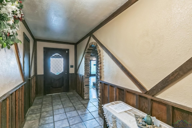 tiled entrance foyer featuring a wainscoted wall, a textured wall, and a textured ceiling