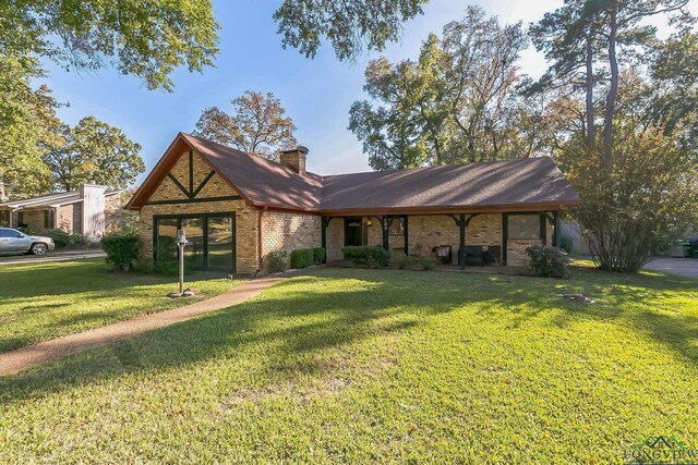 view of front of house with brick siding, a chimney, roof with shingles, and a front yard