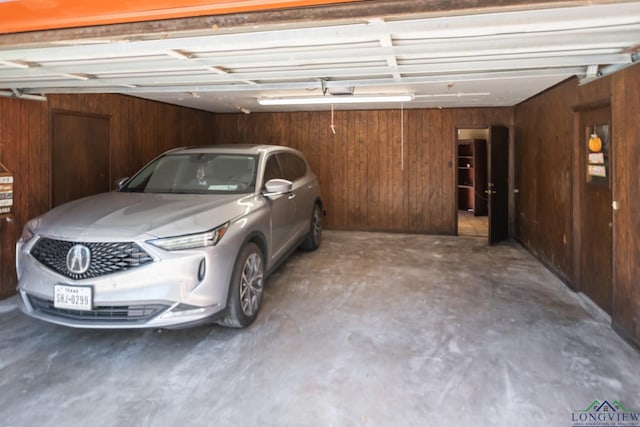 garage with wood walls and a garage door opener