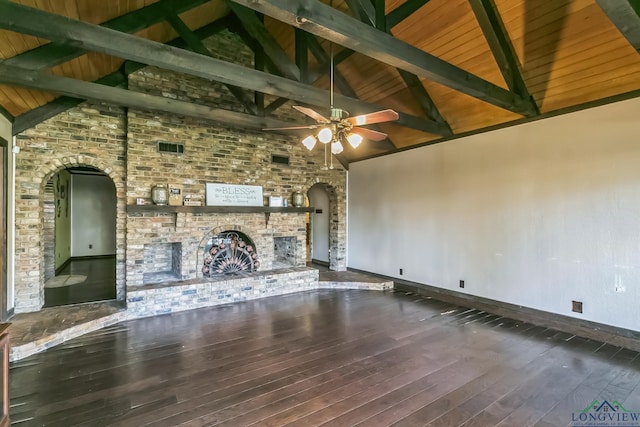 unfurnished living room with beamed ceiling, a brick fireplace, ceiling fan, arched walkways, and hardwood / wood-style floors