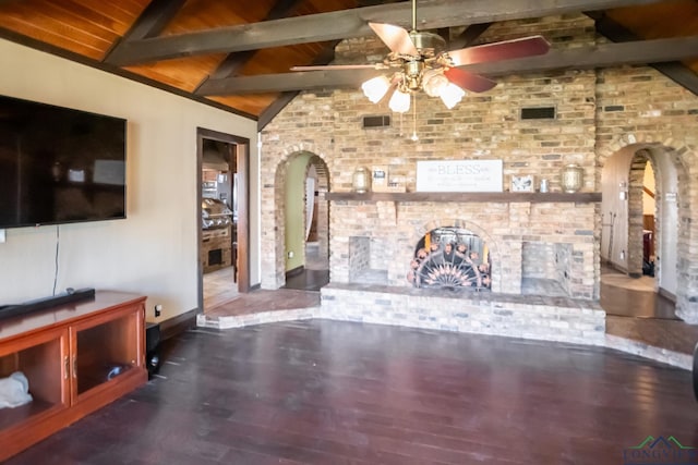unfurnished living room featuring lofted ceiling with beams, wood finished floors, brick wall, arched walkways, and ceiling fan