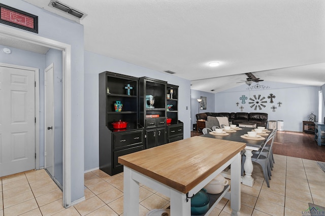 dining room with lofted ceiling, light tile patterned floors, a textured ceiling, and ceiling fan