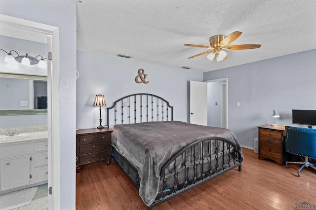 bedroom featuring sink, a textured ceiling, light hardwood / wood-style floors, and ceiling fan