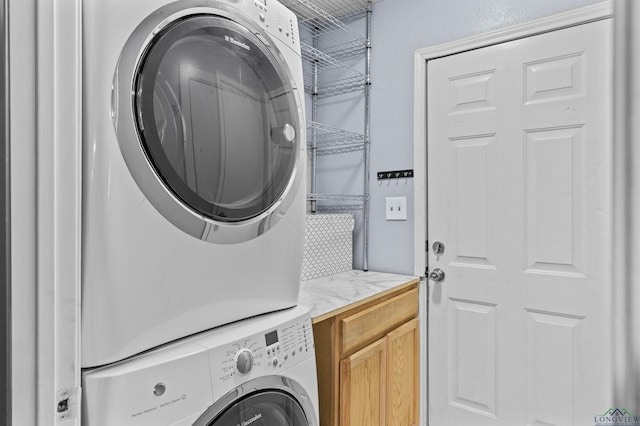 laundry room featuring cabinets and stacked washer and clothes dryer